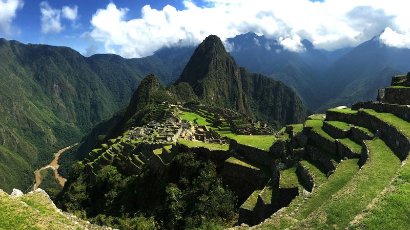 The citadel at Machu Picchu seen along the terraces, peaks and cloud behind it.